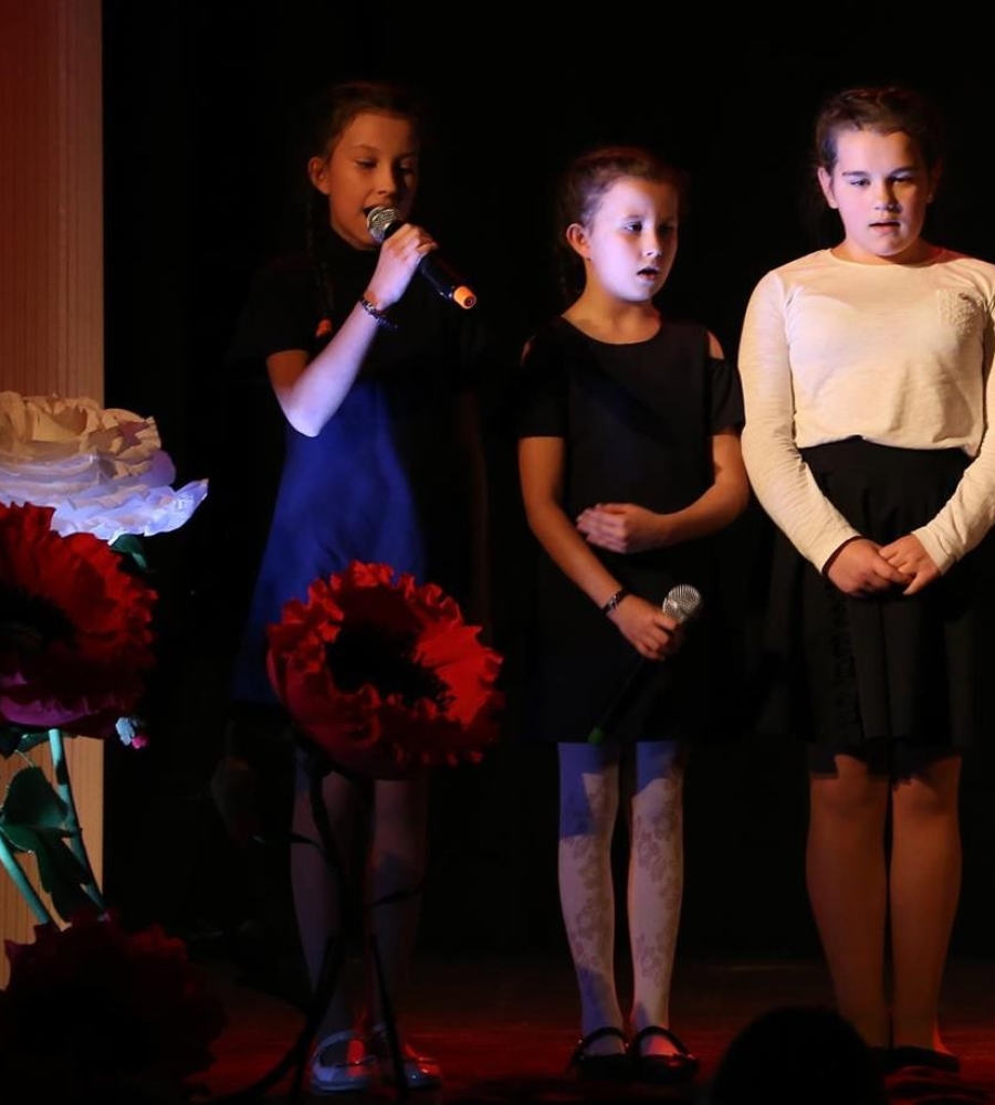trzy śpiewające dziewczynki stojące na scenie