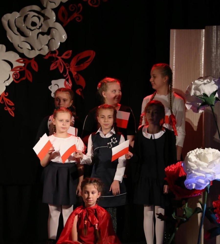sześć dziewczynek stojących na scenie trzyma chorągiewki 