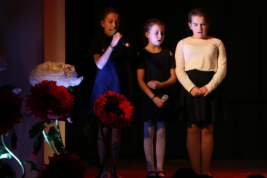 trzy śpiewające dziewczynki stojące na scenie