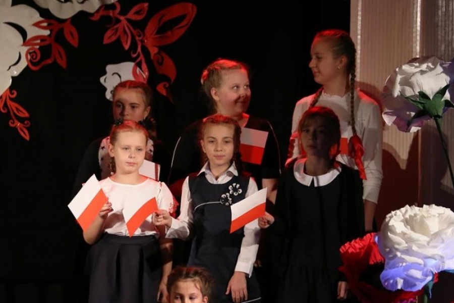 sześć dziewczynek stojących na scenie trzyma chorągiewki 