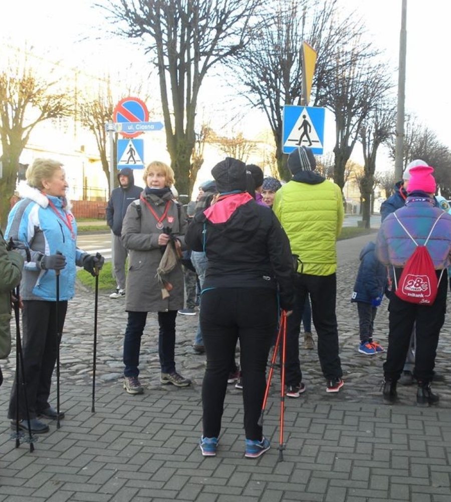 stojąca na chodniku grupa członków Nordic walking