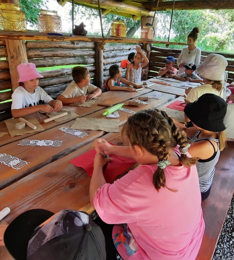 Grupa dzieci siedzi przy stole robiąc prace z plasteliny