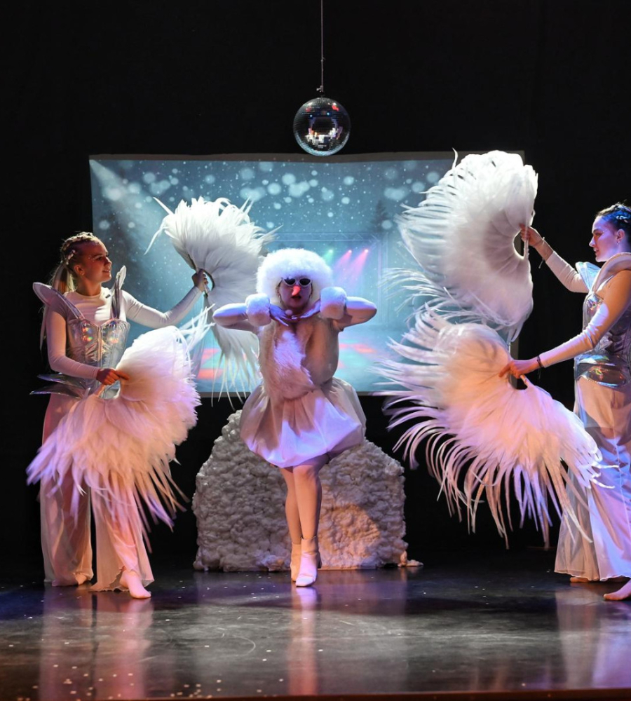 Na scenie tańczą trzy osoby w białych kostiumach i wachlarzami